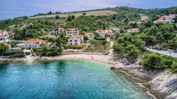 A coastal village with houses on a hillside, a beach, and clear turquoise waters. - Apartments Ivo - Three bedroom apartment with terrace and sea view (A1) (Postira)