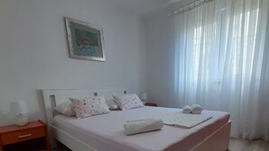 A bedroom with a bed, a nightstand, a painting on the wall, and sheer curtains on the window. - Apartments Ivo - Three bedroom apartment with terrace and sea view (A1) (Postira)