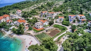 An aerial view of a coastal village with terraced houses, a beach, and clear turquoise waters. - Apartments Ivo - Three bedroom apartment with terrace and sea view (A1) (Postira)