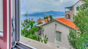 Blick auf die Küste mit Gebäuden, dem Meer und Bergen im Hintergrund.
