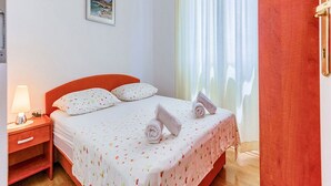 Un letto rifatto con una coperta a fiori, un comodino con una lampada e un quadro appeso al muro.