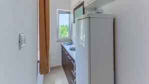 Una cucina compatta con finestra, forno integrato e frigorifero.