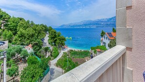 Vista sulla costa con cielo sereno, un sentiero che conduce a una spiaggia e edifici con tetti rossi.
