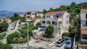 Un quartiere residenziale su una collina, con case a più piani, una strada asfaltata e auto parcheggiate.