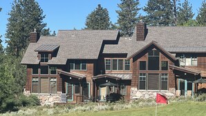Una casa grande de varios pisos con base de piedra, fachada de madera y múltiples ventanas.
