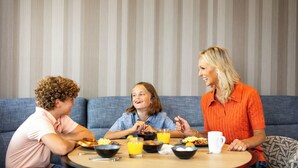 Une famille est assise autour d’une table ronde, et on aperçoit un canapé bleu en arrière-plan.