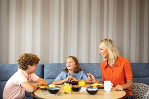 Una familia cenando en una mesa redonda con un sofá azul al fondo.