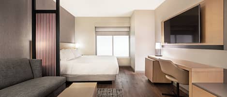 Una habitación de hotel moderna con cama, sofá, escritorio y televisión.