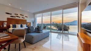 A modern hotel room with a large window, a sofa, a wooden desk, and a bed with a wooden headboard. - Casa Luna del Mar - Private Pool & Beach, FastWifi (Puerto Vallarta)