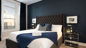 Une chambre d’hôtel moderne avec un grand lit, des murs de couleur sombre et une vue par la fenêtre.