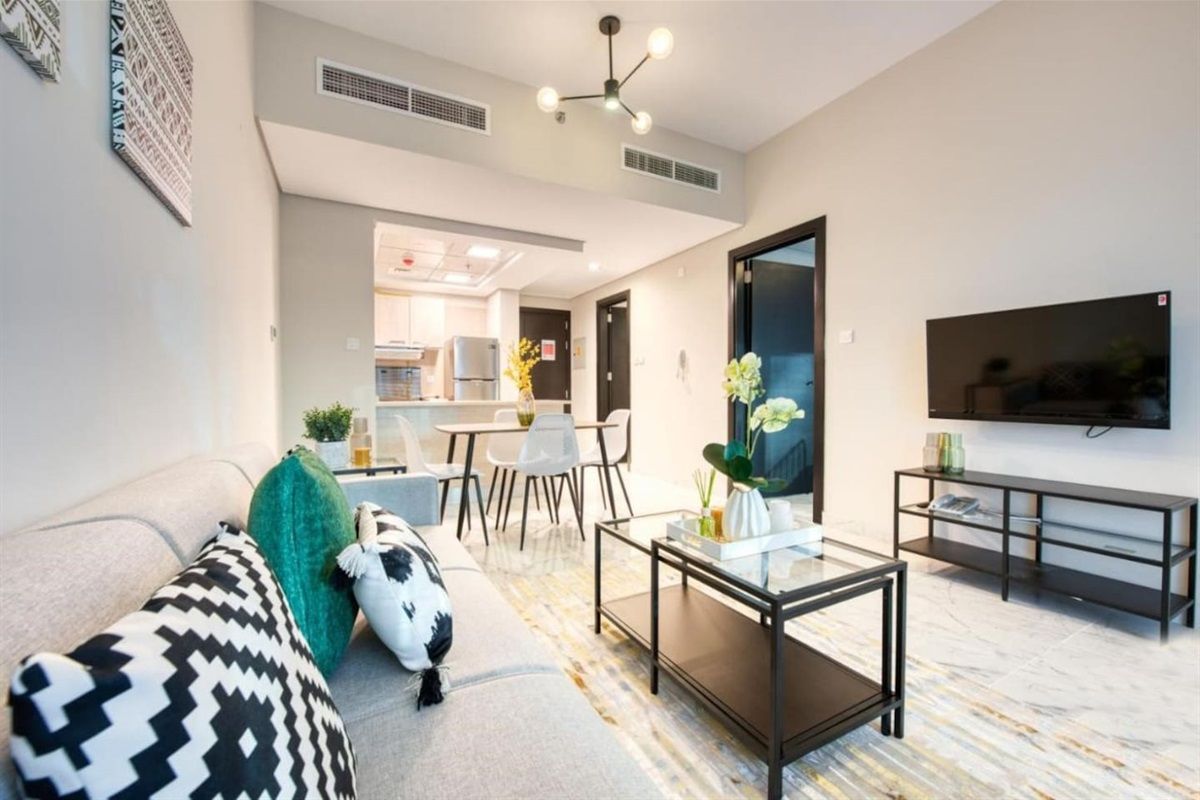 Uma sala de estar moderna com sofá, mesa de centro e televisão de tela plana na parede.