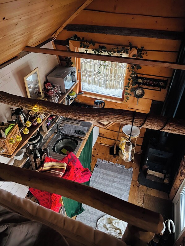 A rustic cabin interior with a kitchen, dining area, and a cozy fireplace.