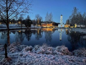 Escena tranquila junto al lago, con una iglesia y edificios residenciales reflejados en el agua.