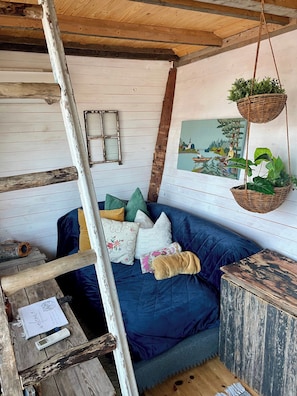 A rustic room with a blue sofa, wooden beams, a hanging plant, and a framed picture on the wall. - Romantic Cabin Right on the Lake With Fire Place (Stjärnsund)