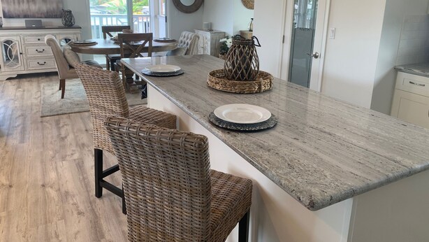 Una cocina moderna con una isla grande, sillas de mimbre y una mesa de comedor.