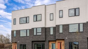 Un immeuble résidentiel à plusieurs étages, doté d’un design moderne, de grandes fenêtres et d’un revêtement combinant brique et métal.