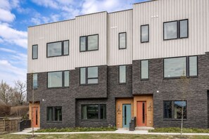 Ein mehrstöckiges Wohngebäude mit modernem Design, große Fenster und eine Kombination aus Ziegel- und Metallverkleidung.