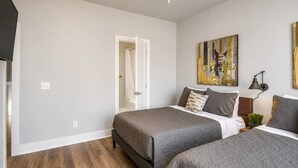 Une chambre d’hôtel avec deux lits, une douche, un tableau et une lampe.