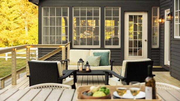 A deck with outdoor furniture, a dining table with a bottle and glasses, and a view of a house with large windows and a door. - Private Estate w/ Heated Pool, Pond & 10 Acres (Accord)