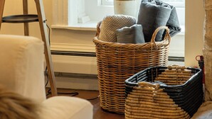A cozy room with a large window, a wicker basket, a lamp, and a white chair. - Private Estate w/ Heated Pool, Pond & 10 Acres (Accord)