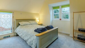 Un dormitorio con cama, una mesita de noche con lámpara, una ventana con vistas y un letrero de salida de incendios.