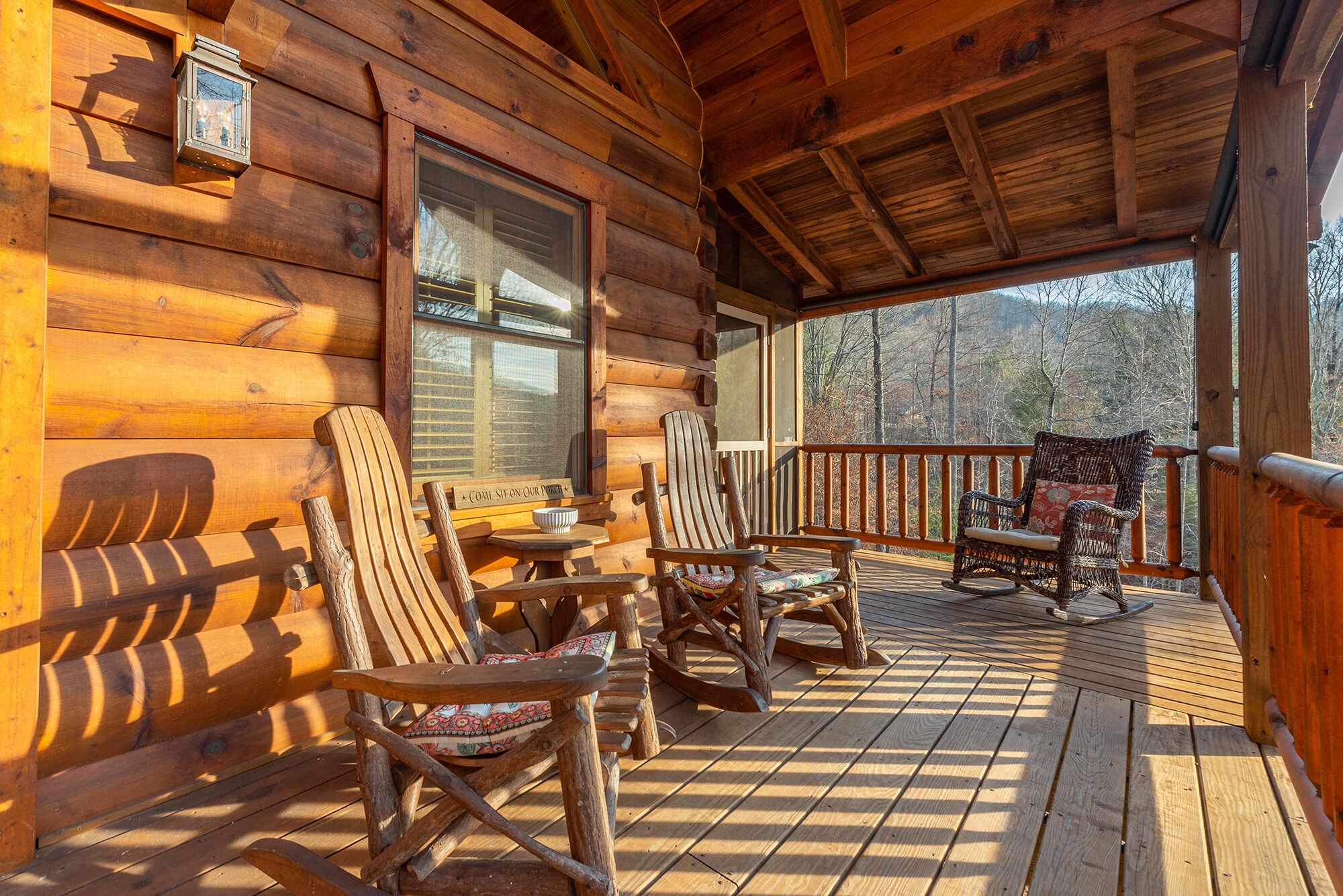 A wooden cabin with a porch featuring rocking chairs and a table.