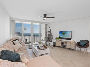 Enjoy the serene sea view from this stylish living room with a sofa, coffee table, and TV.