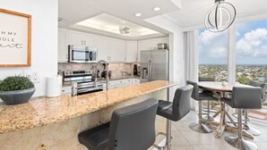 Una cocina moderna con encimera de granito, electrodomésticos de acero inoxidable y un comedor con vistas.