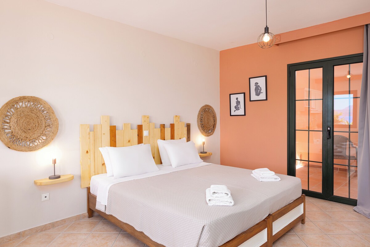 A bedroom with a wooden headboard, a bed with white linens, two bedside tables with lamps, and a large window with a view.