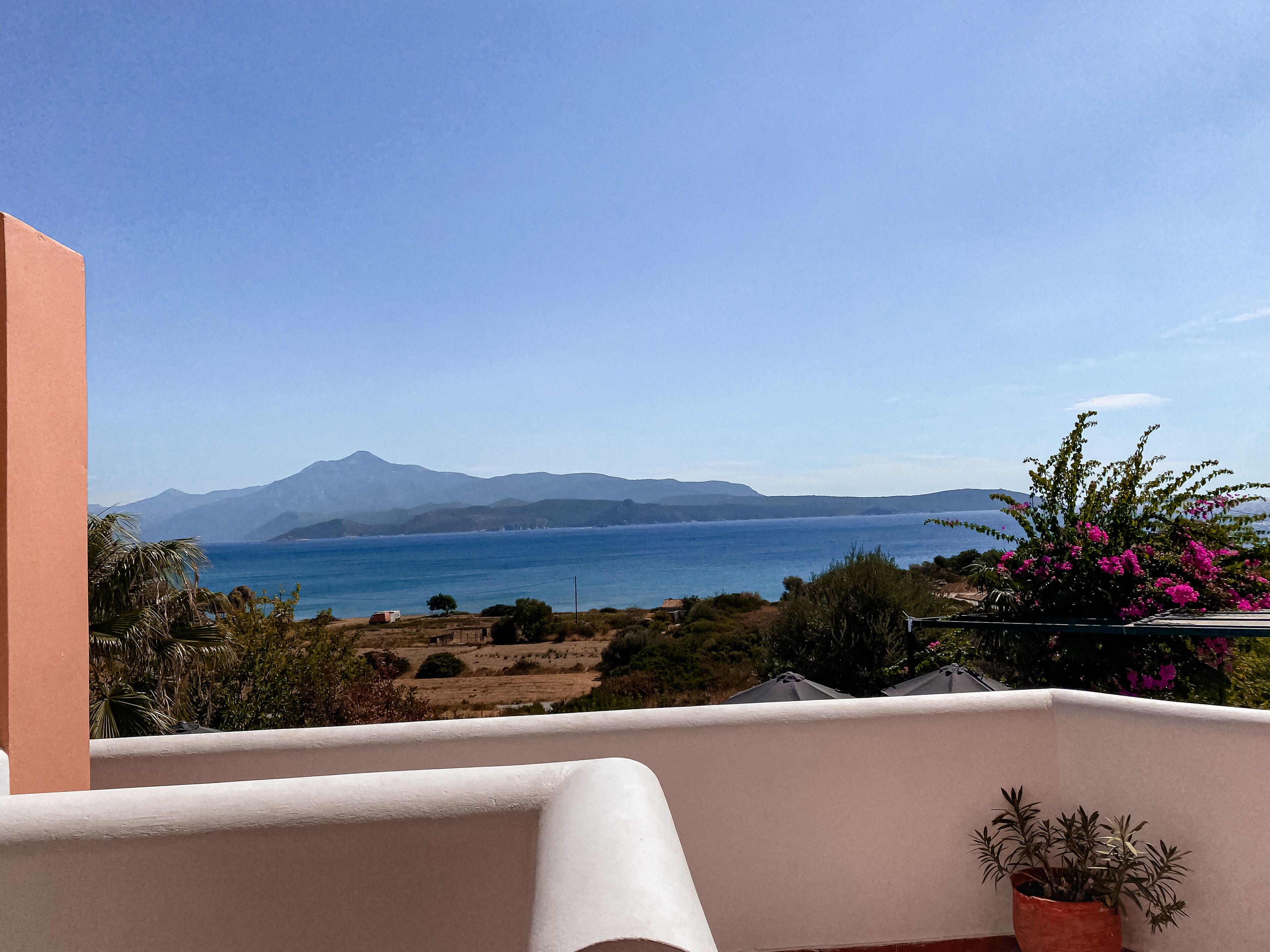 A balcony with a view of the sea and mountains.