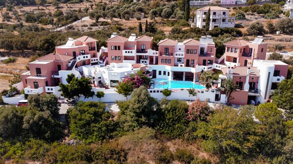 A residential complex with multiple buildings, a central swimming pool, and surrounding greenery.