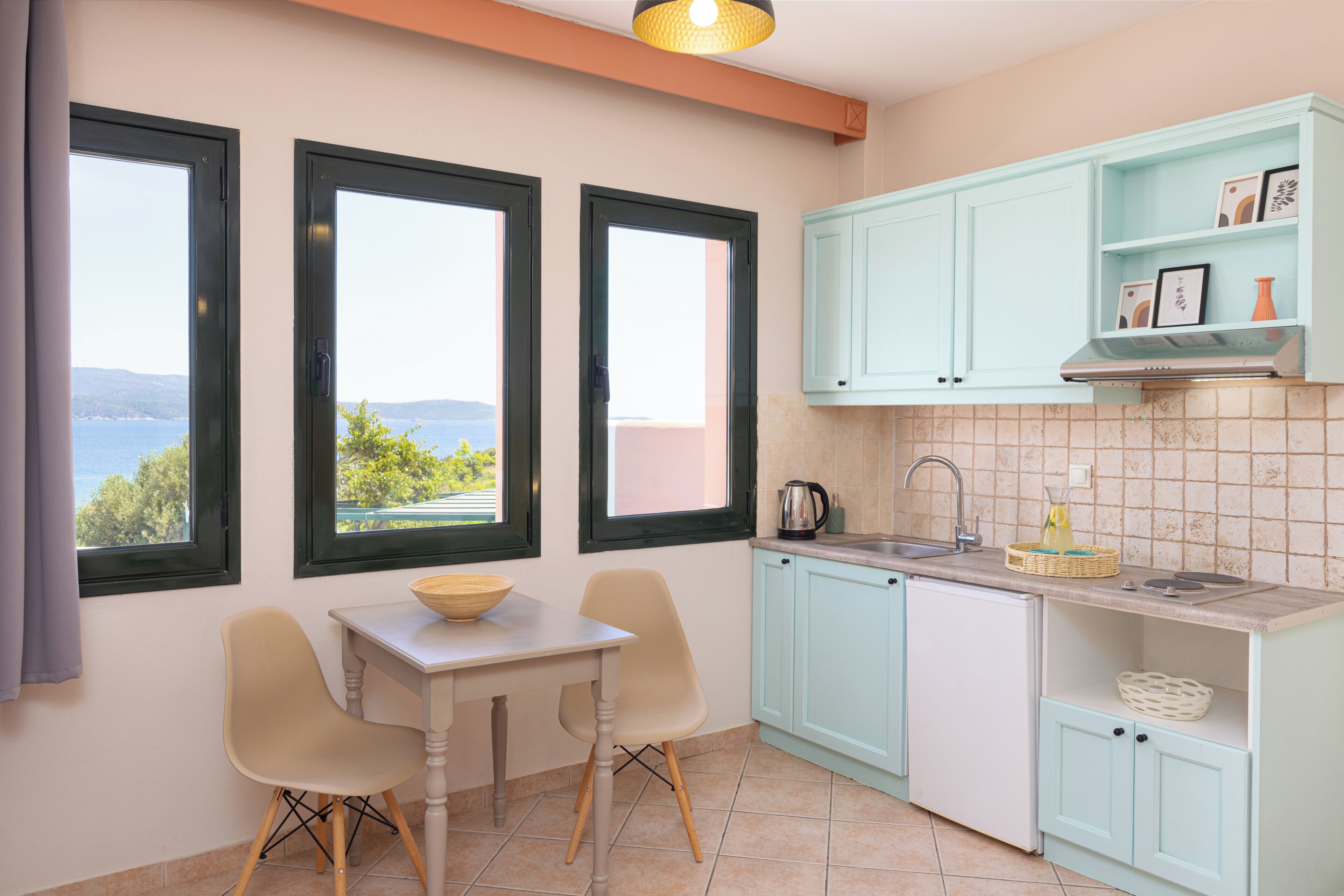 A kitchen with two windows, a table, chairs, and light blue cabinets.