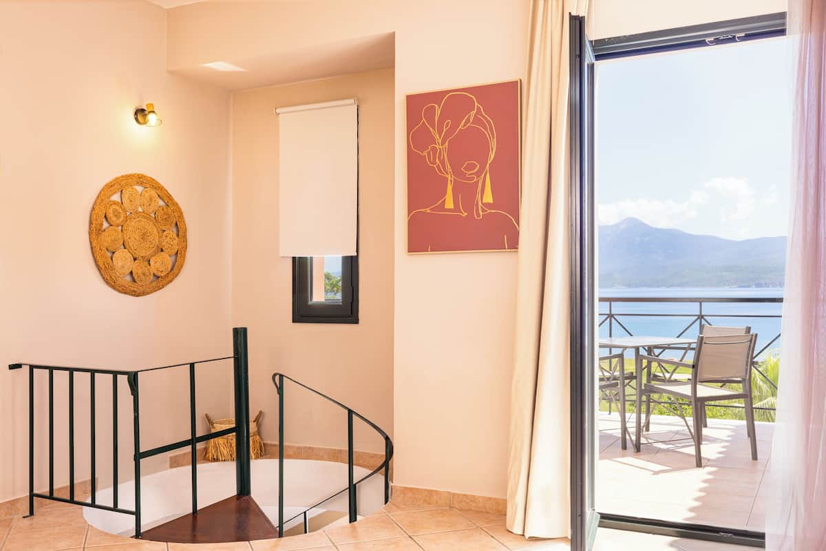 A staircase with a black railing, a wall-mounted light fixture, a framed picture, and a view of a balcony with outdoor furniture.