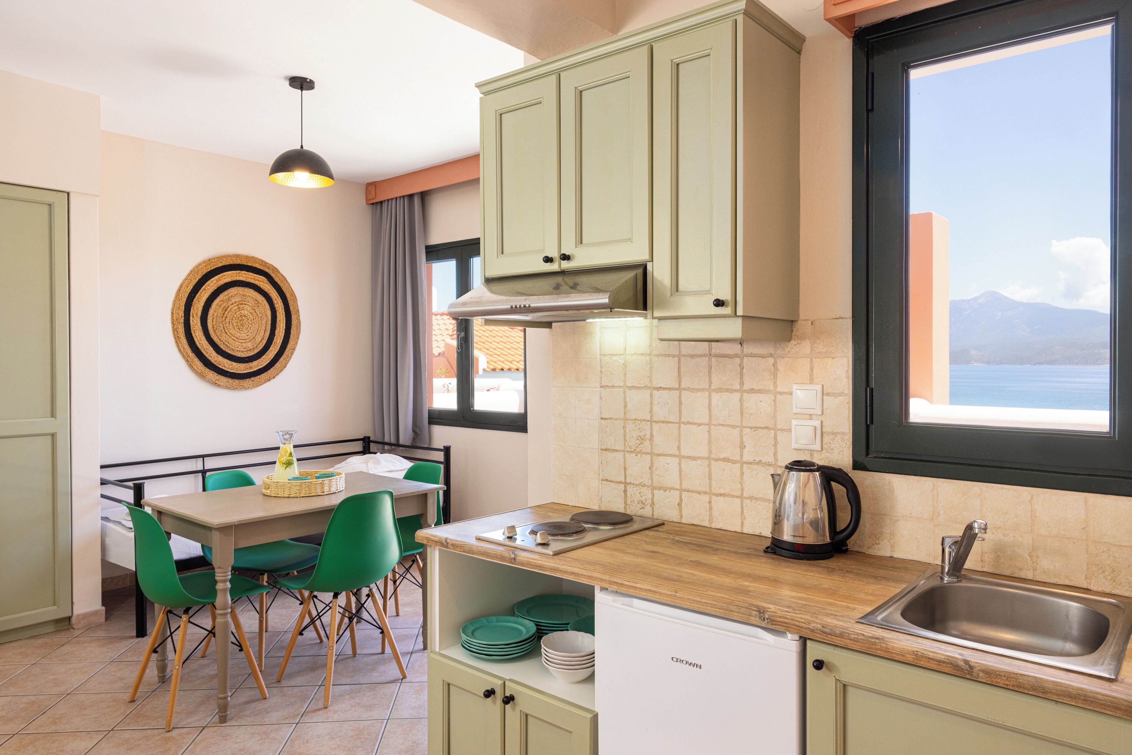 A kitchen with a wooden countertop, a sink, and a window with a view of the sea.