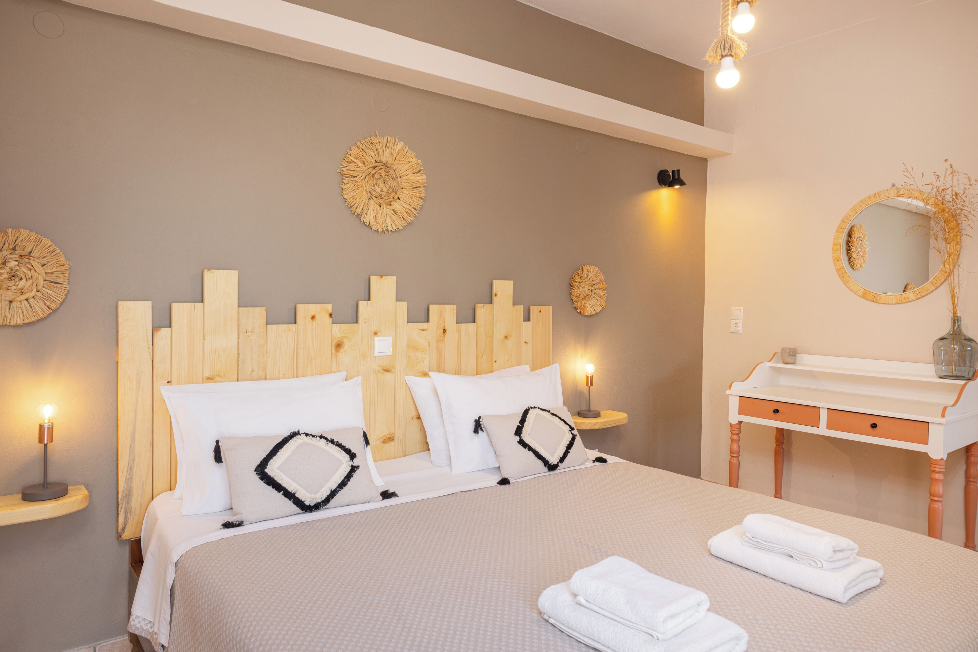 A neatly made bed with white bedding and decorative pillows, a wooden headboard, and a bedside table with a lamp.