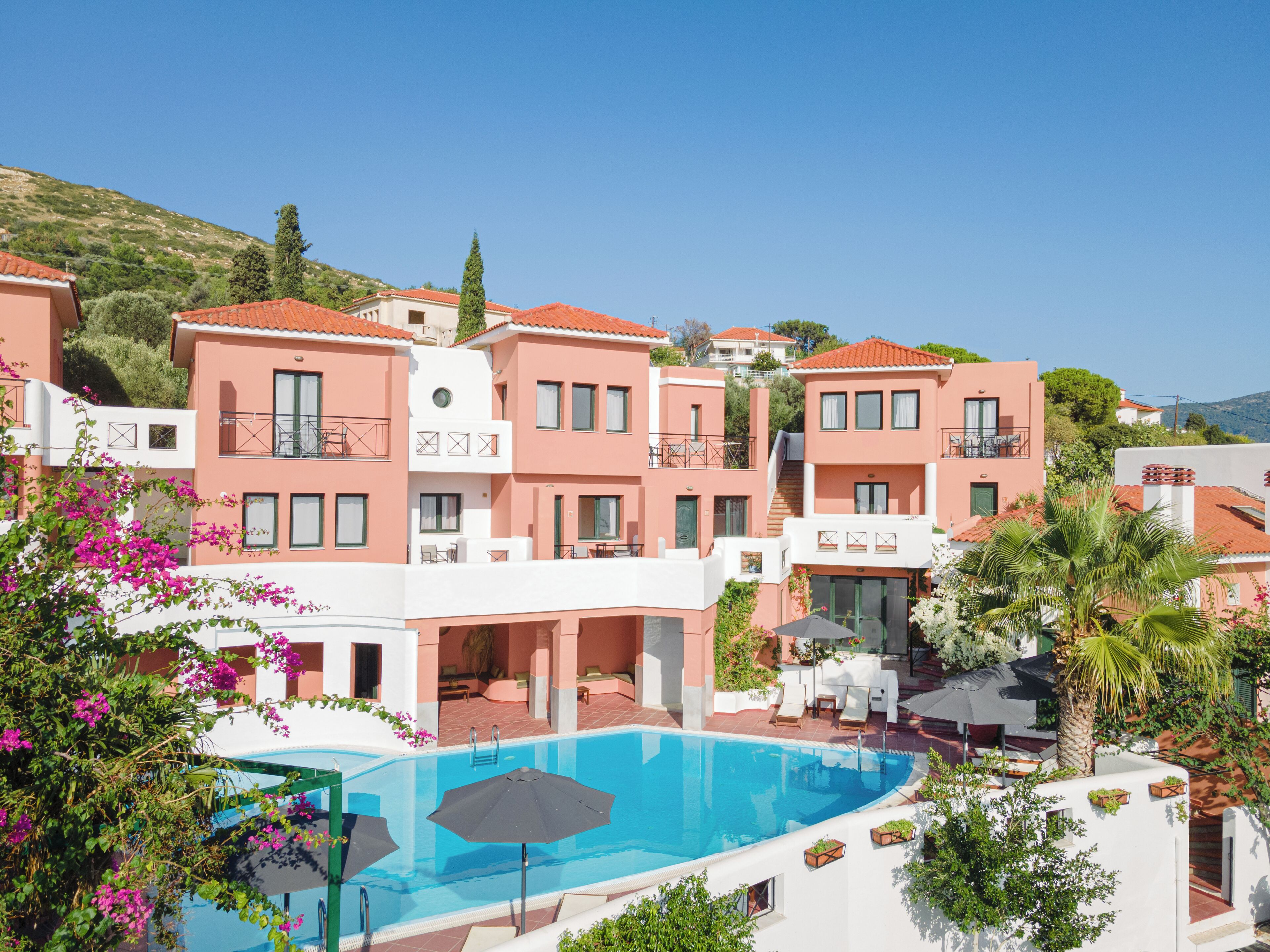 Un resort con varias edificaciones, piscina y abundante vegetación.