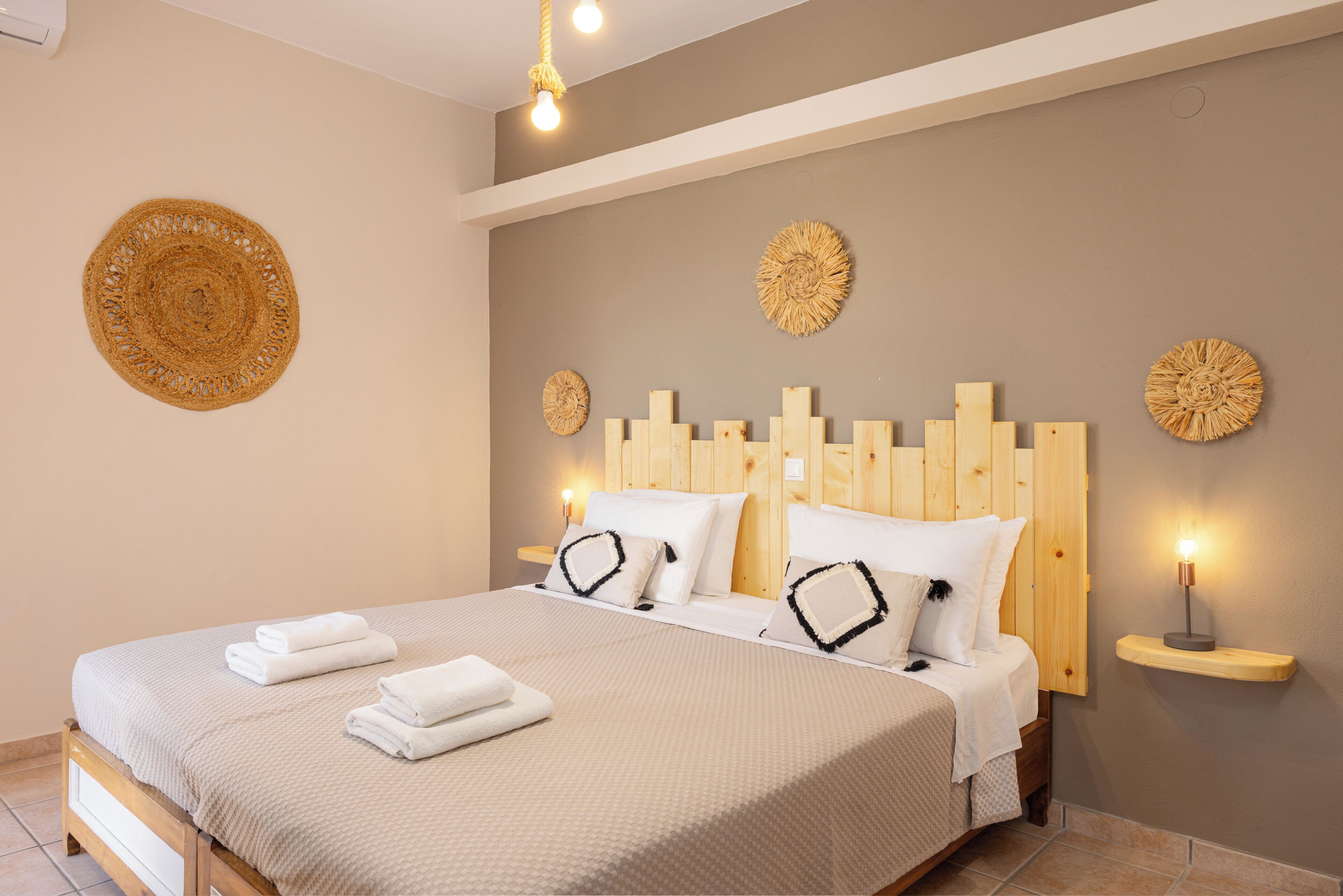 A neatly made double bed with a wooden headboard, two bedside tables with lamps, and decorative wall art.