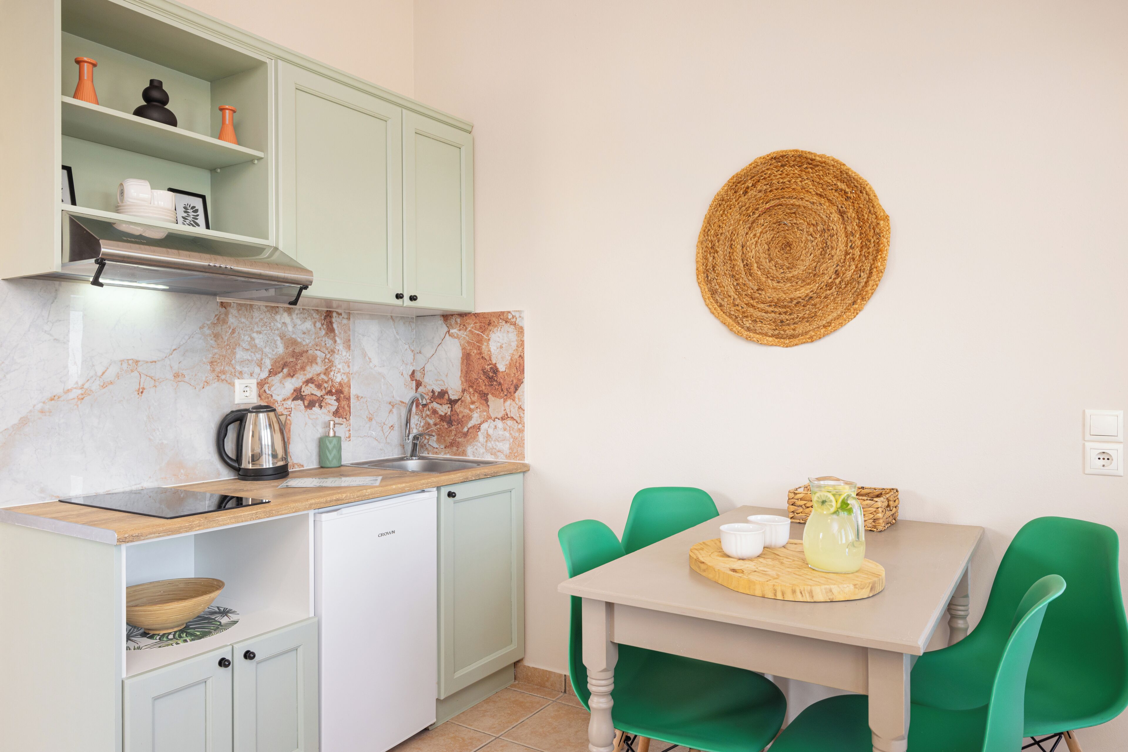 A compact kitchen with a built-in dishwasher, a coffee maker, and a table with chairs.