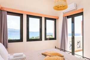 Un dormitorio con cama, vista al mar y un balcón con mesa y sillas.