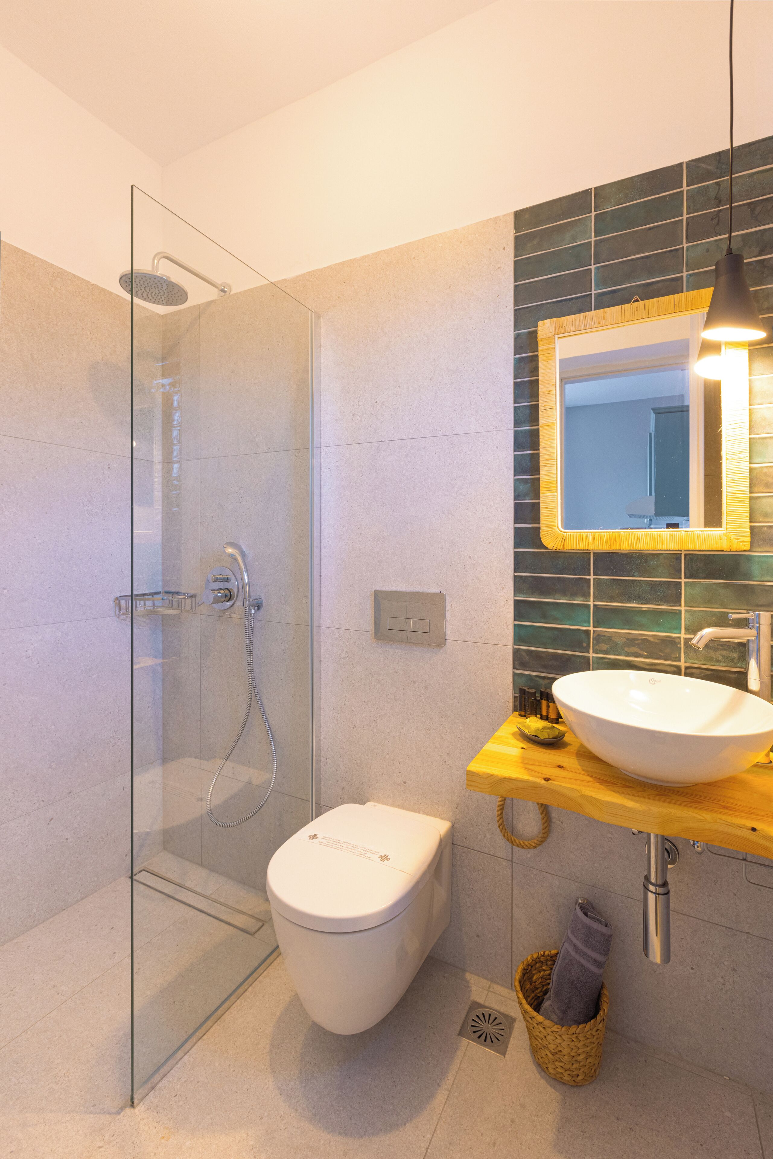 A modern bathroom with a glass-enclosed shower, a white toilet, a wooden vanity with a large sink, and a mirror with a wooden frame.