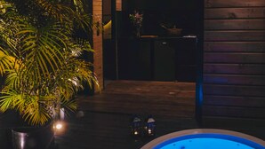 Un espace piscine avec un jacuzzi, une plante en pot et une terrasse en bois.