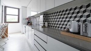 Eine moderne Küche mit weißen Schränken, einer schwarz-weißen Spritzschutzwand, einer Edelstahl-Arbeitsplatte und einem Fenster für natürliches Licht.