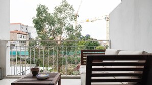 Ein Balkon mit Holztisch, Blumentopf und einer Sitzecke.