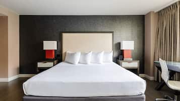 Een hotelkamer met een groot bed, twee nachtkastjes met lampen, een bureau en een stoel.
