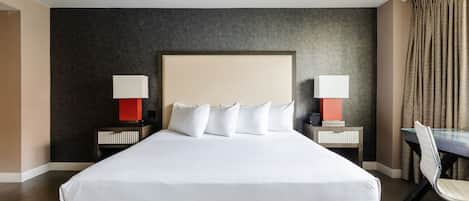 A hotel room with a large bed, two bedside tables with lamps, a desk, and a chair.
