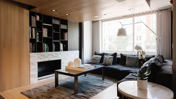 A modern living room with a fireplace, a sofa, a coffee table, and a bookshelf. - 2500 Penn, a Placemakr Experience (Washington)