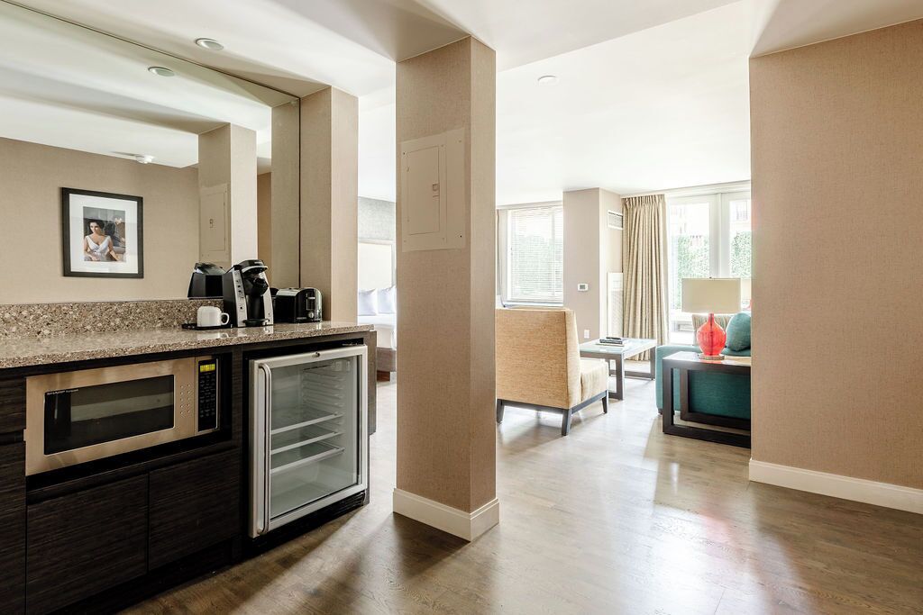 A modern kitchen with built-in appliances, a seating area with a sofa and armchairs, and a window providing natural light.