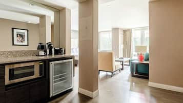 A modern kitchen with built-in appliances, a seating area with a sofa and armchairs, and a window providing natural light.