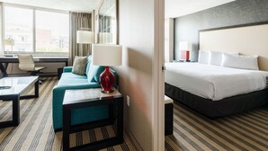 A hotel room with a bed, a sofa, a desk, and a lamp. - 2500 Penn, a Placemakr Experience (Washington)