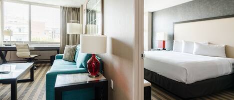 A hotel room with a bed, a sofa, a desk, and a lamp.